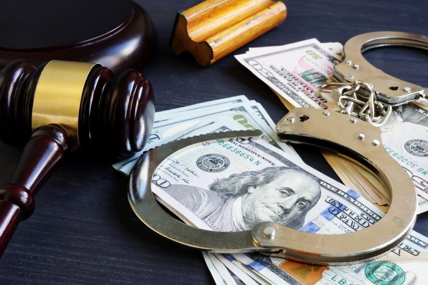 A depiction of bail bonds including cash, a gavel, and cuffs