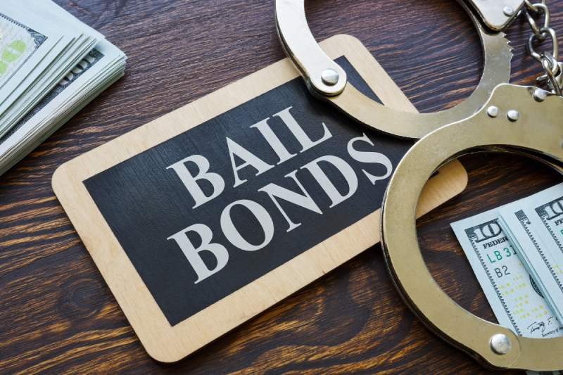 Bail bond notice with one hundred dollar bills and handcuffs on table
