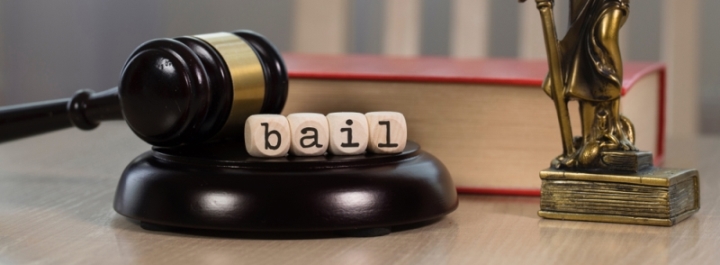 Word bail in black letters on white wooden dice on wooden gavel with justice figure in background