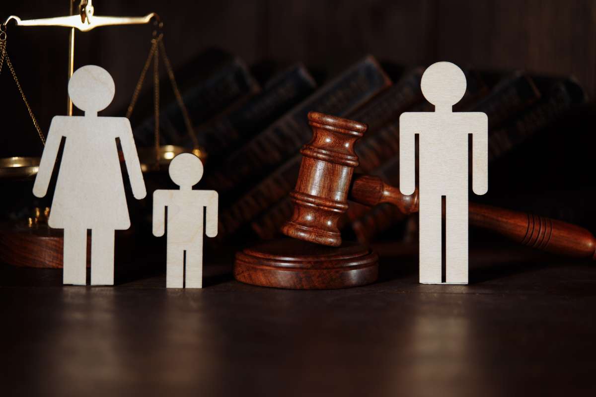 Cardboard family figures female and child with gavel between them and male figure custody battle