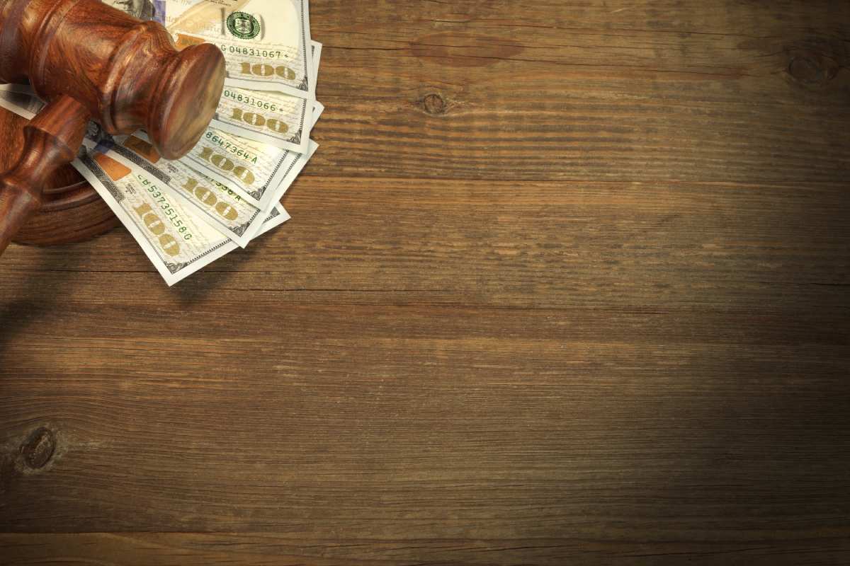 Judges gavel on top of row of 100 dollar bills on wooden table