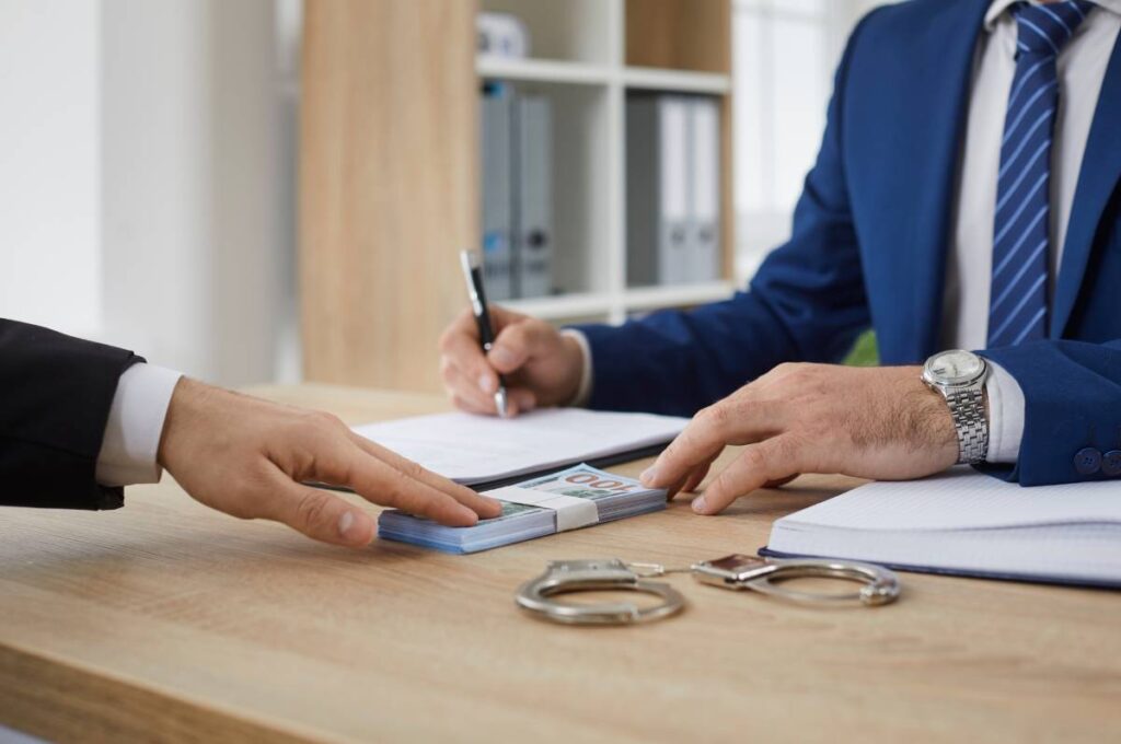 Men in suits negotiating a bail bond with handcuffs on table cash between them