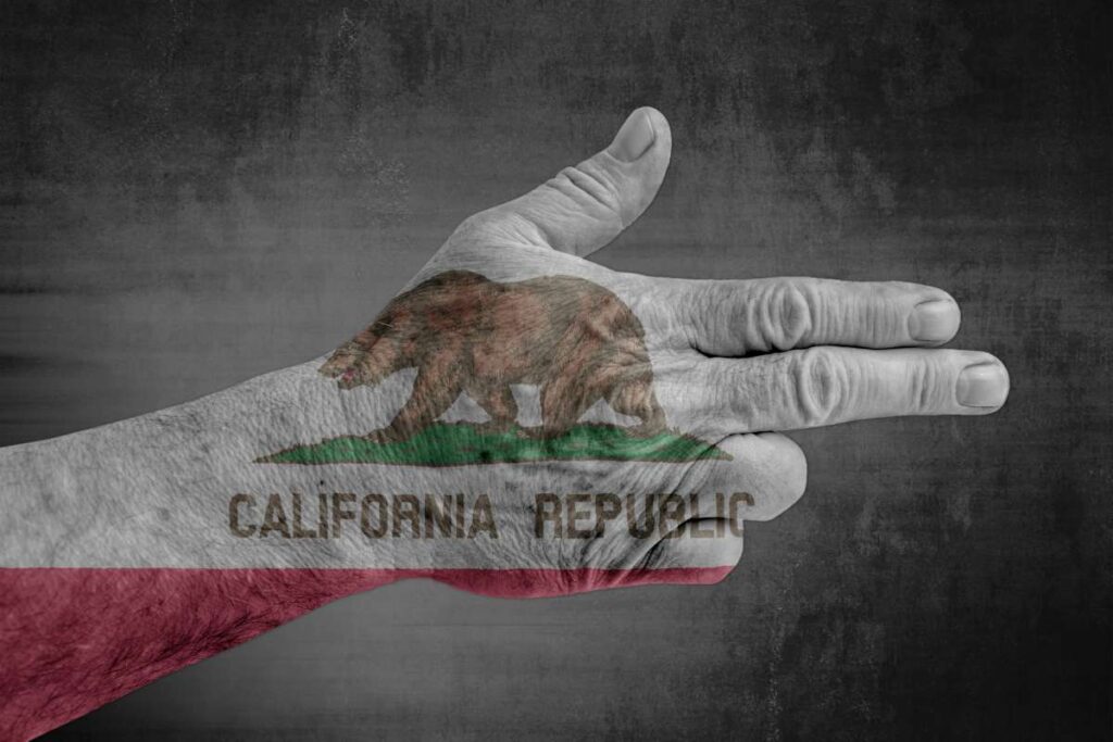 A black and white photo of a hand in a gun shape with the California flag projected in color over the top