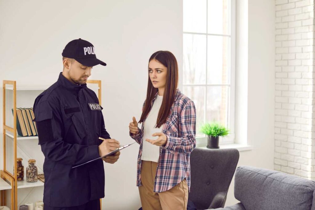 A tenant in an apartment speaks to a police officer, who takes notes