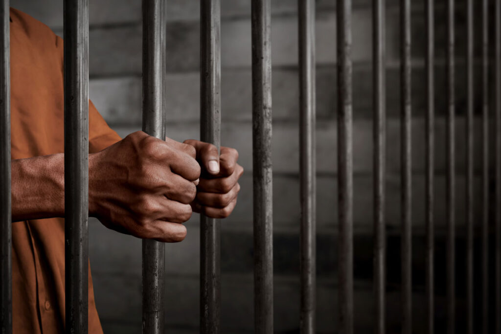 A man’s hands holding prison bars