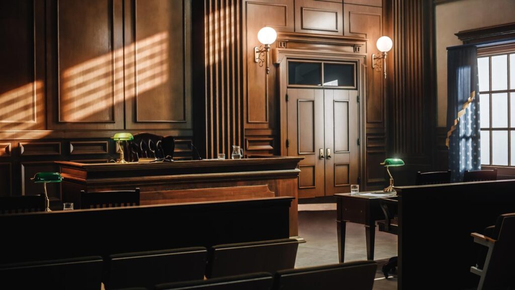 A courtroom sits empty as sunlight streams through the windows.