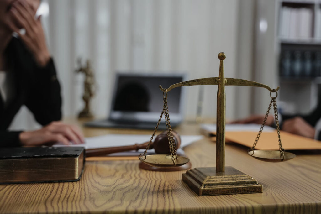 The scales of justice sit in the foreground of a legal office.