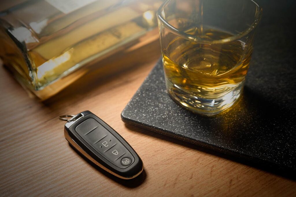 A glass of alcohol next to a car key fob.