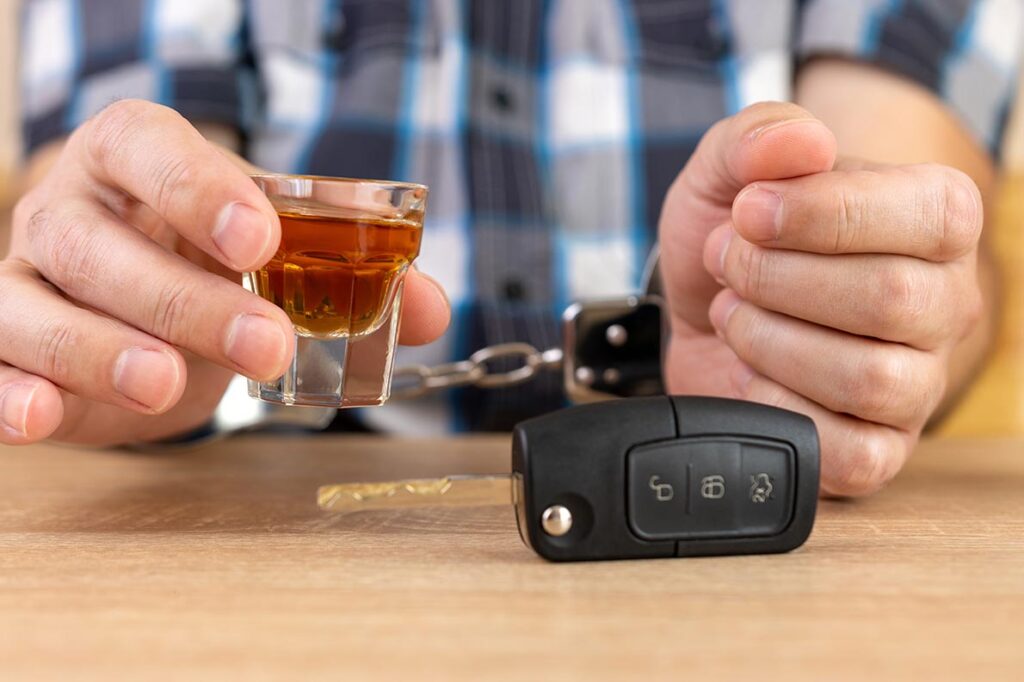 A man in handcuffs holding a shot glass