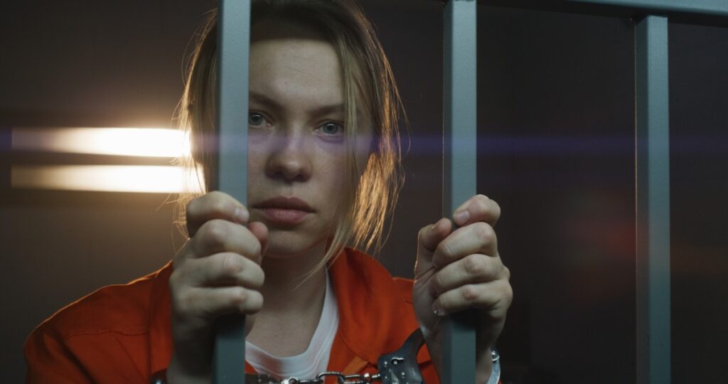 A female prisoner holding the bars of her cell.