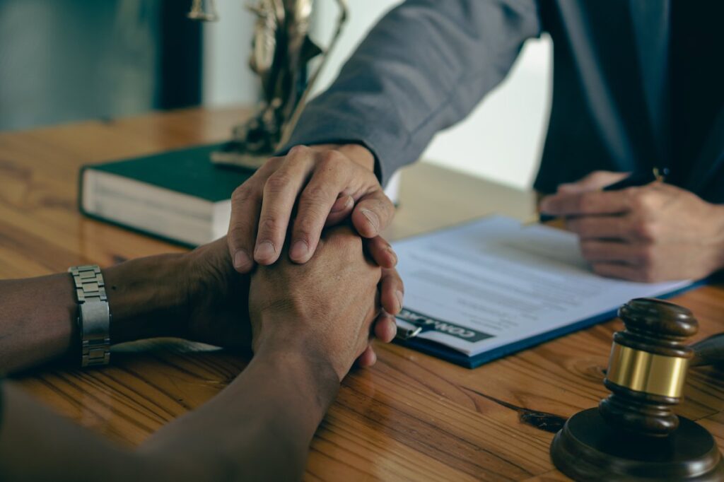 A close-up view of a lawyer holding a client’s hands during a meeting.